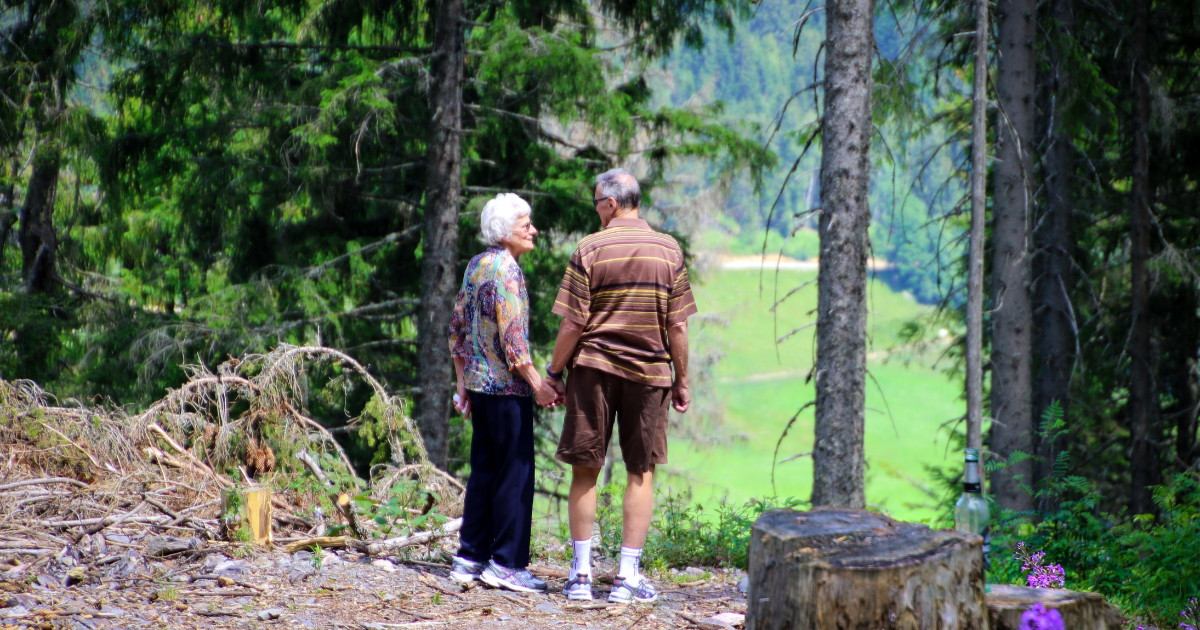 Elderly couple standing in woods enjoying in-home care